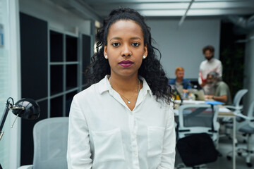 Portrait of a young business serious woman looking at camera and confident at work at office. Confident people and professional corporate empowered latin lady