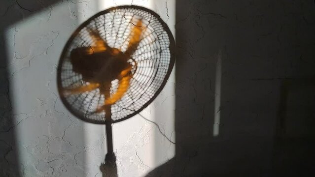 Primer plano de una sombra de un ventilador en movimiento en una pared con un fondo blanco.