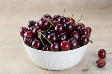 A bowl of fresh red cherries on a beige background. Fruit background