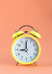 Yellow alarm clock on a colored orange background. Minimalism. Concept of time, planning.