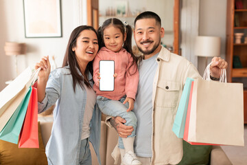 Asian Family Showing Phone Screen Holding Shopper Bags At Home