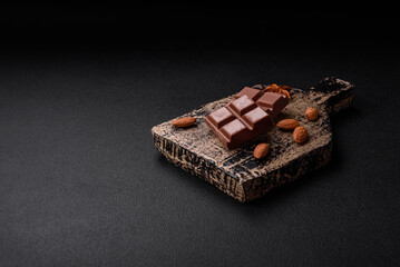 Delicious sweet milk chocolate broken into cubes on a wooden cutting board