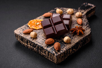 Delicious sweet black chocolate broken into cubes on a wooden cutting board