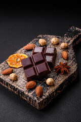 Delicious sweet black chocolate broken into cubes on a wooden cutting board