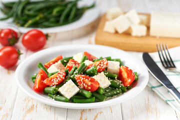 Fresh summer green beans salad bowl with tomatoes, feta, and sesame.