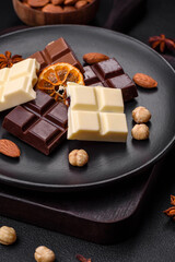 A mix of several types of delicious sweet chocolate broken into cubes on a black plate