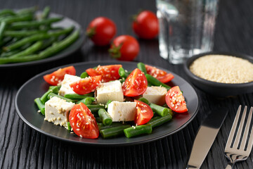 Fresh vegetarian vegetable salad with with tomatoes, feta and sesame seeds on a white wooden table, healthy food.