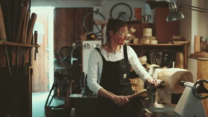 Craftswoman carving wood in a carpentry workshop 
