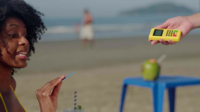 NFC credit card payment. Woman at the beach paying with contactless credit card with NFC technology. Wireless money transaction. Wireless payment

