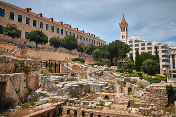 Naklejka premium Ruins of Roman bath surrounded by modern buildings of Downtown Beirut. Roman Baths of Berytus, ancient archaeological site. Grand Palace and Saint Louis Des Capucins cathedral at background