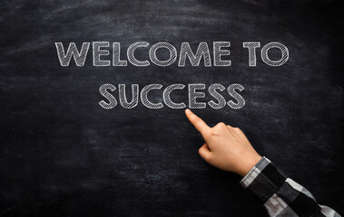 The hand points to the inscription on the board Welcome to Success