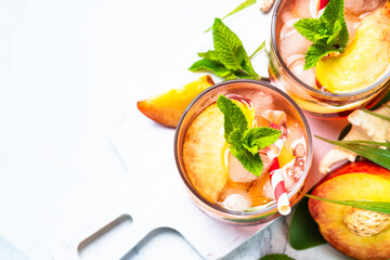 Peach cocktail, iced peach tea, fruit drink with tropical leaves. Top view with space for design.