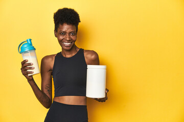 Obraz premium African woman in sportswear with protein powder and shake.