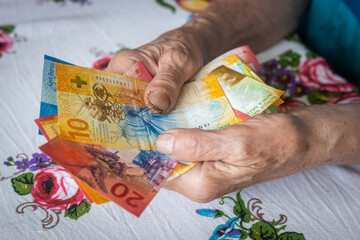 pensioner holds a bunch of low denomination banknotes in her hands, Cost of living for a senior citizen in Switzerland, Pensions and the Swiss social system for the elderly - obrazy, fototapety, plakaty