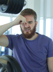 Portrait of tired exhausted sad man unhappy guy in the gym, feeling bad during training 