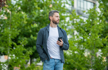 Naklejka na ściany i meble photo of man texting on phone in hands. man texting on phone outdoor.