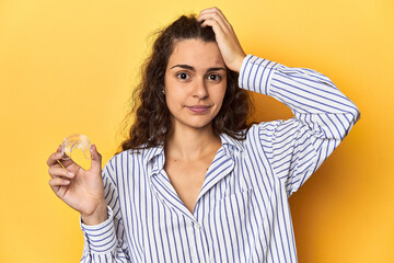 Woman holding an invisible teeth corrector being shocked, she has remembered important meeting.