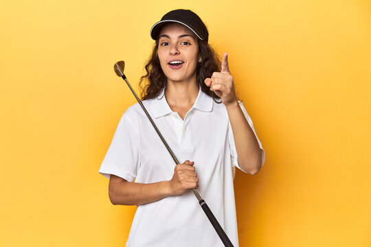 Golfer woman with cap, golf polo, yellow studio, having an idea, inspiration concept.
