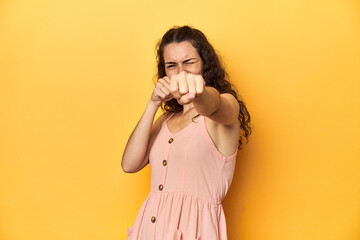 Obraz premium Young Caucasian woman, yellow studio background, throwing a punch, anger, fighting due to an argument, boxing.