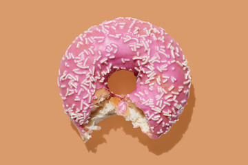 pink donut with glaze on orange pastel background