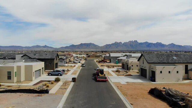 Aerial Drone Following a Construction Vehicle in New Southwest Neighborhood. aerial drone view following a flatbed truck carrying a construction vehicle in a growing southwest subdivision in NM