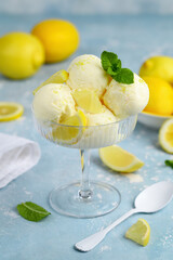 Lemon yoghurt ice cream balls in a glass bowl with lemon slices and mint. Selective focus