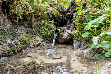 A stream of running water from a forest well creates water ripples at the surface of the lake