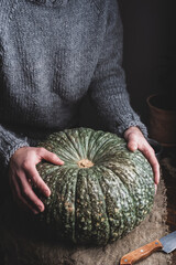 Hands Putting Green Pumpkin on Table