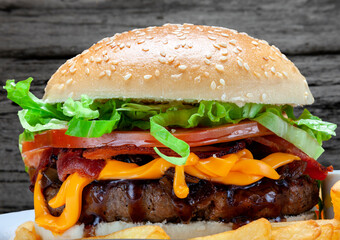 Burger with grilled meat, tomato, onion, lettuce, bacon and french fries