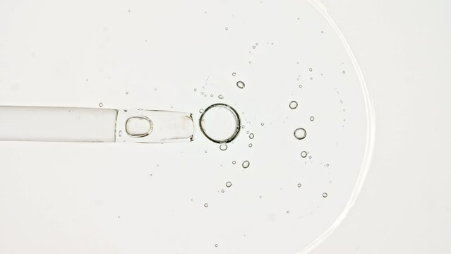 Transparent cosmetic gel fluid, serum with molecule bubbles oil in pipette drips on a white background. Macro Shot of Natural Organic Cosmetics, Medicine. Production Close-up. Slow Motion. 4k. 