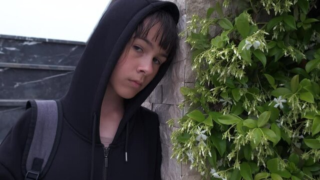 Teenage depression. A teenage girl in a hood looks indifferently into the camera.