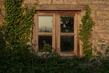 Fototapeta na wymiar Abandoned cottage house window in the sunset light