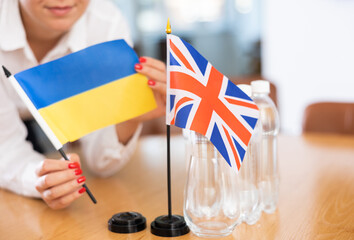 Little flag of Great Britain on table with bottles of water and flag of Ukraine put next to it by...
