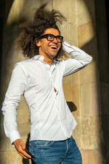 Stylish Urban Communication: Afro-Haired Guy in White Shirt and Glasses. City Charisma: Energetic Afro-Haired Guy Engaged in Phone Conversation. Dynamic Conversations: Afro Style in the Urban