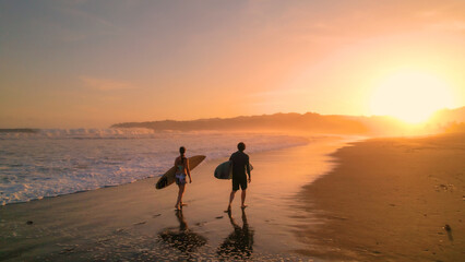 AERIAL: Surfers watch big breaking waves from beach after sunset surf session