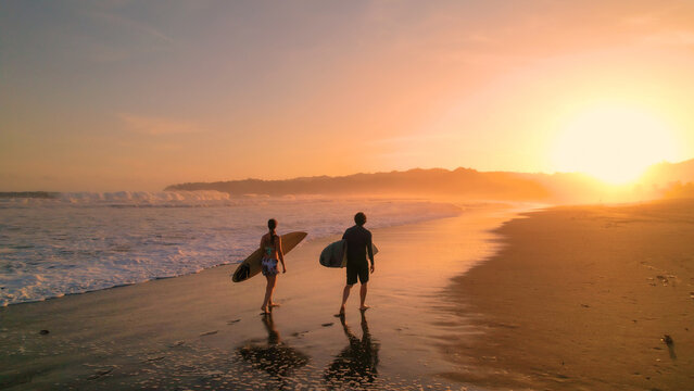 AERIAL: Surfers watch big breaking waves from beach after sunset surf session - Powered by Adobe