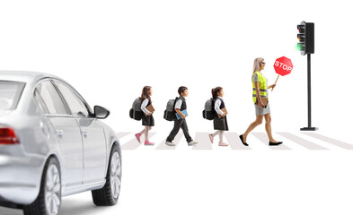 Teacher and children in safety vests crossing a street and carrying stop sign at pedestrian crosswalk