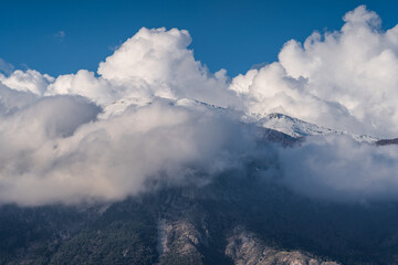 Snowcapped mountain top against blue sky and clouds