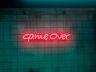 game over neon sign on a dark tile background