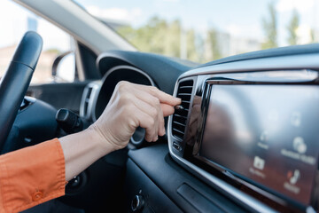 Close-up hand of a woman driver adjusting car conditioner temperature