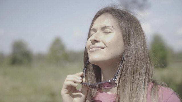 the girl takes off her sunglasses and exposes her face to the sun