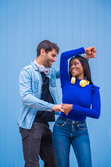 Obraz premium Multiethnic dancer couple of Caucasian man and black ethnic woman on a blue background having fun, dancing salsa and latin music