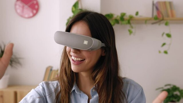 Excited young businesswoman enjoying metaverse experience wearing virtual reality googles at studio office. Virtual reality and metaverse gaming concept