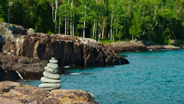 Zen Stacked Rocks On A peaceful Beach With blue Water and green minnesota forest