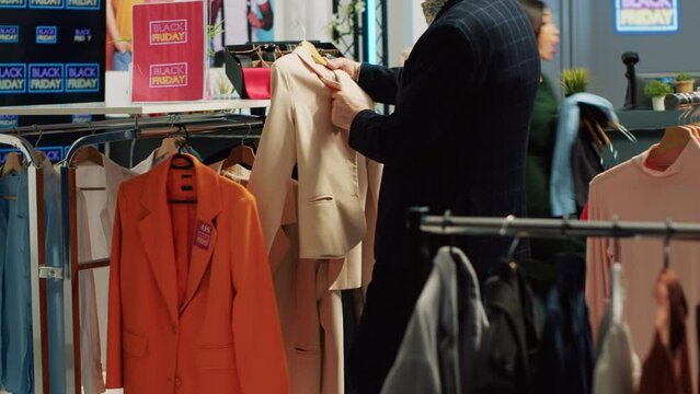 Shoppers running around retail store on black friday, in a hurry to grab clothes cheap for sales season. Busy clothing store filled with customer rushing to get best promotions on items.