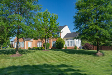 Large, beautiful, single-family brick country house. Large lawn and green trees.