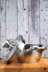 Stainless steel saucepan with a glass lid on a wooden table.