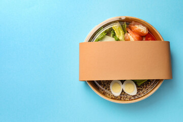 Tasty food in container on light blue background, top view. Space for text