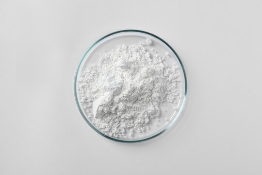 Petri dish with calcium carbonate powder on white background, top view