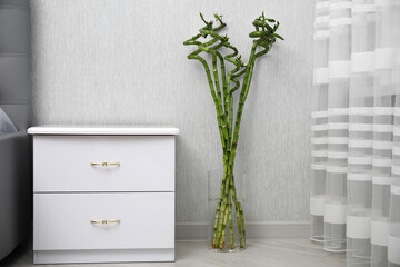 Vase with beautiful green bamboo stems on floor indoors